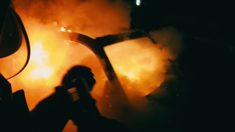 firefighter in action. fire and rescue. flames in the night. adrenaline scene in first person. point of view of the fireman. a team of firefighters extinguishes a fire that is destroying a car