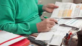 Close-up of old man hand holding green pen and writing down information on sheet paper. Senior man working with documents at home and making financial calculations. Male accountant in retirement and - Powered by Shutterstock - Get 15% off with code: PIKWIZARD15