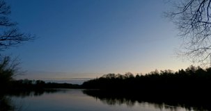 Sun rising over an river with blue skyes timelapse