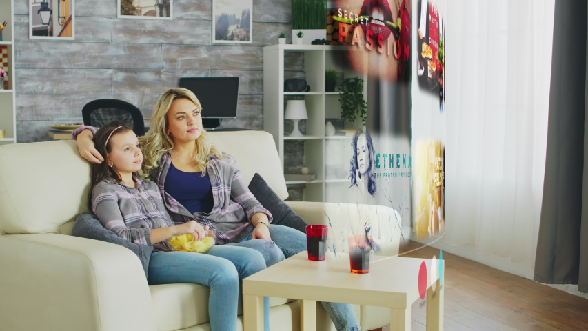 Family of mother and daughter in living room watching a hlogram projection of smart TV in fron of them