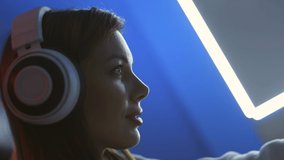 The professional gamer girl with headphones sitting in the neon room
