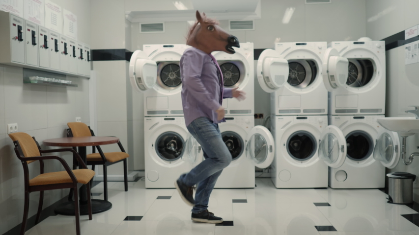 Joyful Man in mask horse Dancing Cheerful In Laundry Room. Man Dancing Viral Dance And Have Fun In Laundry Room. Happy Guy Enjoying Dance, Having Fun Together, Party Halloween. Slow Motion. Halloween Royalty-Free Stock Footage #1051136200