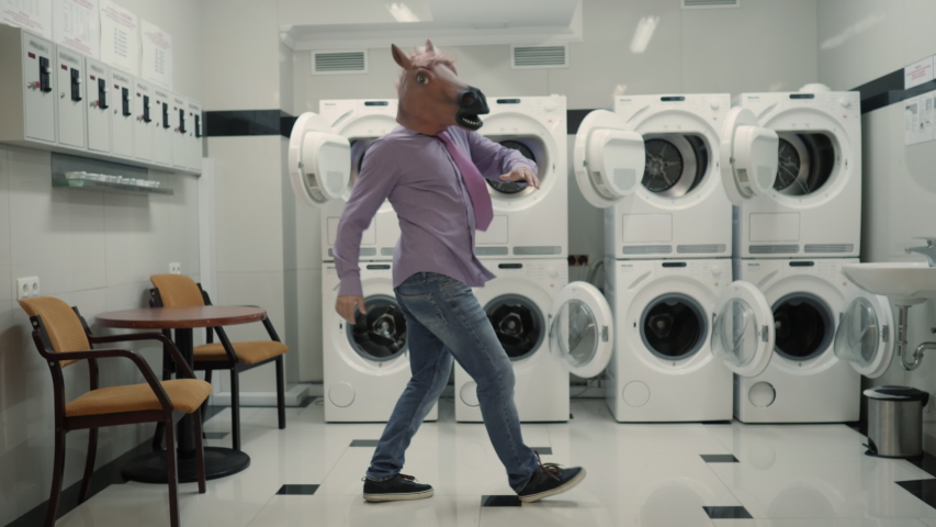 Joyful Man in mask horse Dancing Cheerful In Laundry Room. Man Dancing Viral Dance And Have Fun In Laundry Room. Happy Guy Enjoying Dance, Having Fun Together, Party Halloween. Slow Motion. Halloween Royalty-Free Stock Footage #1051136200