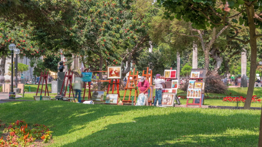 Miraflores central park timelapse. Place for relax with green trees and lawn in Peruvian capital. Artists selling paintings. People sitting on benches and walking around. Lima, Peru