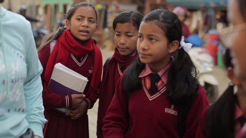 Kathmandu, Nepal - 25 November 2019: Asian Indian Nepalese teenage girls stand outside and talk with a female volunteer. Blurred background closeup