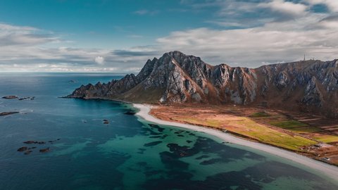 Aerial view of the magnificent Royken mountain on the island of Andoya, Norway. Transparent blue waters of the bay, white sandy beach, thin clouds above.