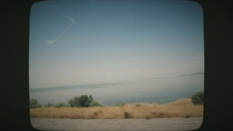 White seagulls flying above the Great Salt Lake on a sunny day, beautiful scenery. View from a car's window. VINTAGE FILM.