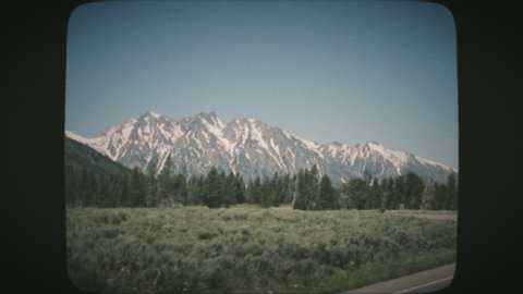 POV Driving through the Grand Teton National Park, beautiful peaks and scenery, sunny day. View from a car's window. VINTAGE FILM.