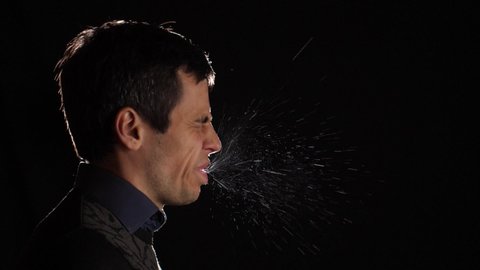 Man sneezes and particles of saliva fly up in the air