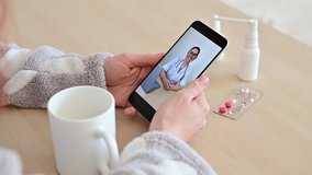 Unrecognizable woman on online consultation with a doctor on a cell phone. The girl is sick and talks to the attending physician on a video call from home. Close-up of the screen.