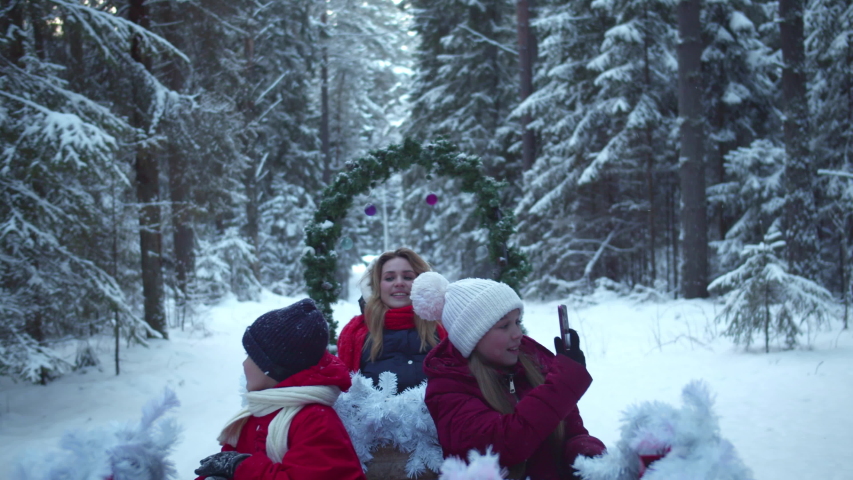 Family sledding and taking pictures on cell phone