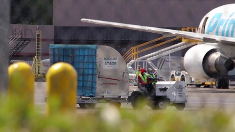 PORTLAND, OREGON / USA - April2020: People on airport tarmac moving a pallet with cargo that belongs to Amazon during the stay at home order restrictions representing essential workers have to work.