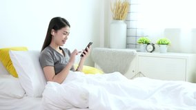 Beautiful young asian woman in grey T-shirt are video calling by mobile phone with her friend, family or boyfriend for social distancing policy. Self quarantine, coronavirus, work from home concept