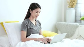 Beautiful young asian woman in grey T-shirt are video calling by laptop with her friend, family or boyfriend for social distancing policy. Self quarantine, coronavirus, work from home concept