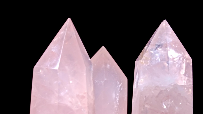 Three Rose quartz and Crystal on rotates on a black background