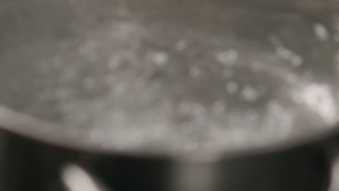 Slow motion handheld shot of boiling water in pot closeup