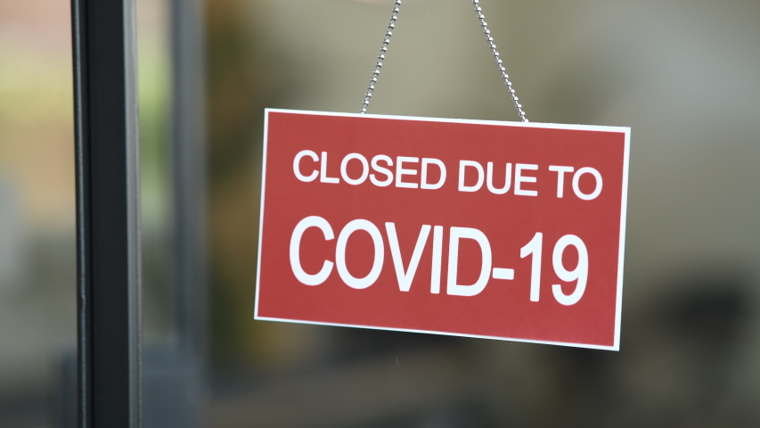Temporarily closed sign for Covid-19 in small business activity. Information notice sign about quarantine measures. Close up on a red closed placard in the window of a shop for coronavirus. | Shutterstock HD Video #1051196821