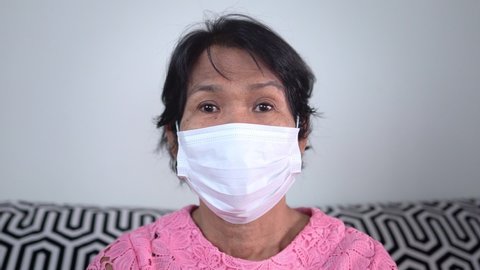 Elderly woman with protection mask isolated at home.