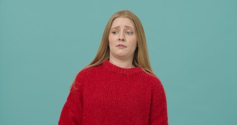 
Annoyed young woman with long blond hair dressed in a red sweater showing fuck you gesture with middle finger isolated over blue background. Concept of anger and irritation
