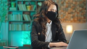 In the office in quarantine business woman have a online interview with her workers she wearing protective mask after she finished the conversation looking straight to the camera. Shot on ARRI Alexa