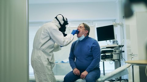 Senior man is getting his saliva taken for the analysis. Coronavirus pandemic, 2019-ncov, the concept of coronavirus.