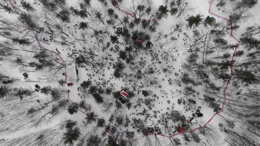 Winter party in the woods in Traverse City Michigan 4K drone shots over forest and open woods in winter snow covered scene looking down at campfire with lots of people at event