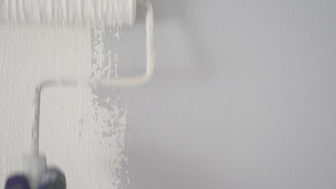 Painter Painting a House Wall with a White Paint Roller..
