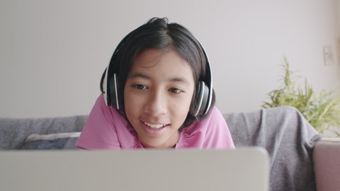 Asian girl video call online via the internet tutor on the tablet, Asia child is study and greeting good morning teacher while sitting in the living room at home and sunlight. Concept learning at home