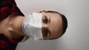 woman in mask on a white background, closeup. vertical video.
