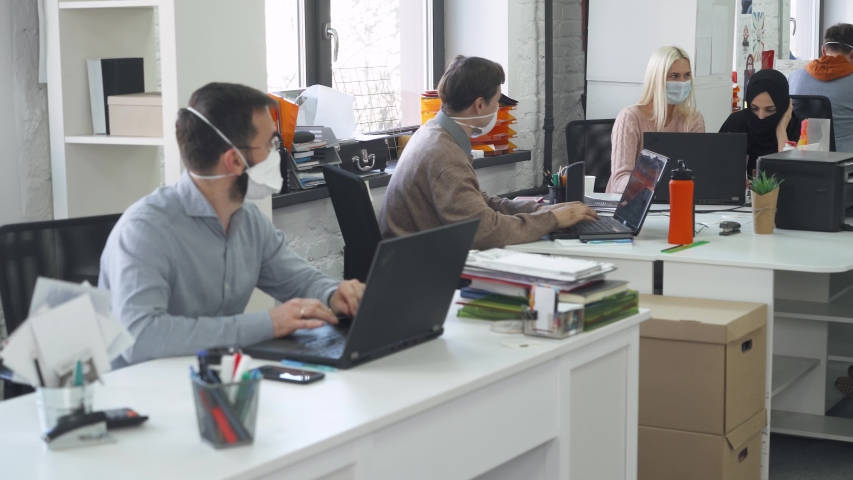 Modern international office, working and communicate in an open space, office workers and managers in medical masks working at computers, protection from the virus, working during the pandemic. | Shutterstock HD Video #1051228531