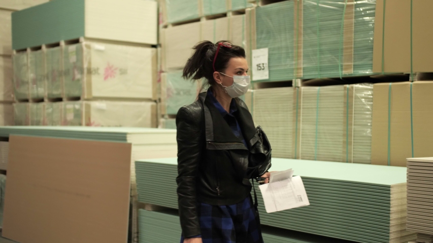 Girl in a medical mask selects a product in a construction store. Coronavirus