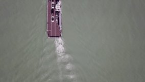 Ferry boat heading with drone on reflective surface, blue water, with cars on board 4K video, waves and froth in water
