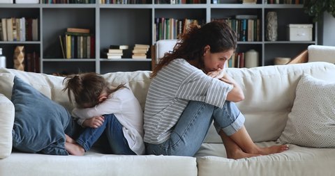 Upset young mom and child daughter turn back ignore each other, avoid talk, feel depressed about bad relationship sitting on sofa at home after family conflict. Parents and children arguments concept.