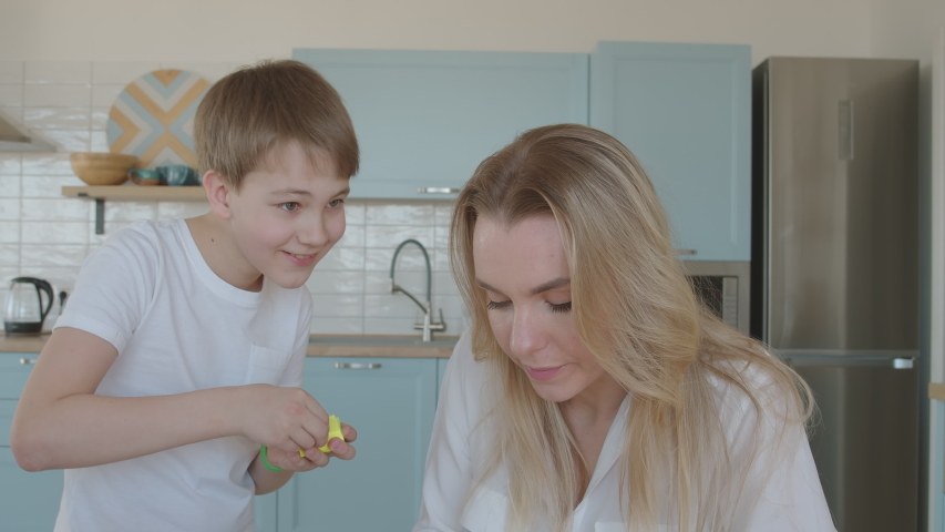 Joyful boy distracts his mother working from home. Kid funny game.