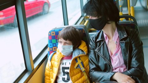 Family adapting free movement. Mom accompanies son in protective masks on face, public transport bus. Adaptation of society to quarantine coronavirus infection COVID-19. 
CZ, Prague airport, 26.4.2020