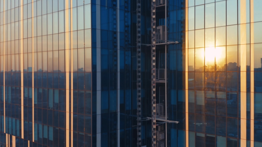 Aerial elevator shot of the modern glass skyscraper exterior with sunshine and reflection on the windows Royalty-Free Stock Footage #1051275715