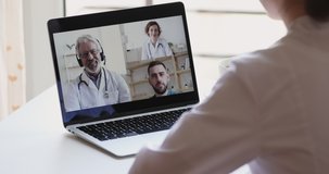 Female medical worker participate online webcam conference on laptop screen. Doctors group discuss healthcare during medic group video call virtual training webinar concept. Over shoulder closeup view