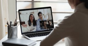 Over shoulder view of young woman video calling friends couples during social distance quarantine. Happy millennial people group enjoy conference chat virtual meeting on laptop screen using pc app.