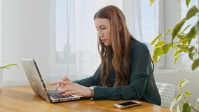 Young, cute business woman sitting in the office and using laptop. Young woman working with a laptop. Female freelancer connecting to internet at home.