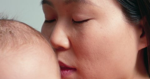 SLO MO ECU Studio portrait of woman kissing baby son (6-11 months)