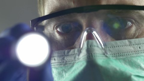 Doctor Using Flashlight on Patient's Eyes Wearing Surgical Mask Glasses POV