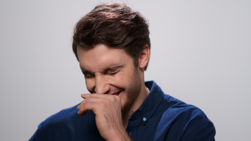 Portrait of happy man posing on white background. Close up handsome man laughing at camera in slow motion. Smiling student in studio. Joyful man with positive emotion