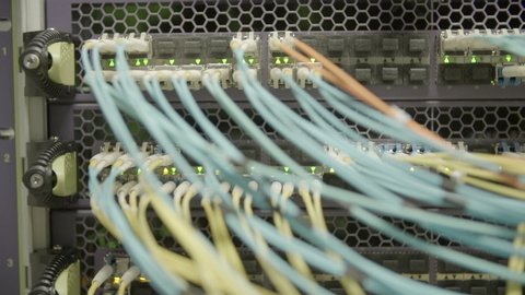 Close-up panning shot of network cables attached to cloud computing system with blinking lights in server room - Silicon Valley, California