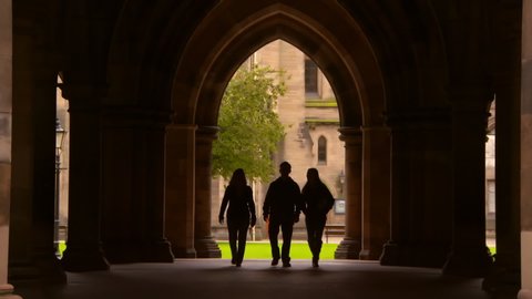 Lockdown shot of silhouette people walking in public university archway - Glasgow, Scotland