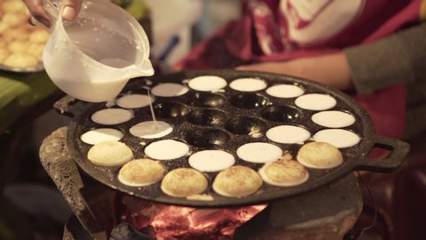 Close-up midsection of woman preparing coconut pancake at street market in city - Luang Prabang, Laos