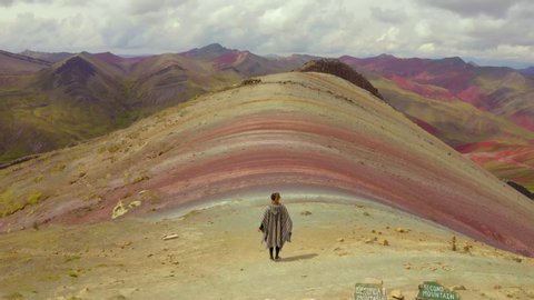 Aerial view of woman walking on mountain against cloudy sky, idyllic view of landscape on sunny day - Rainbow Mountain, Peru