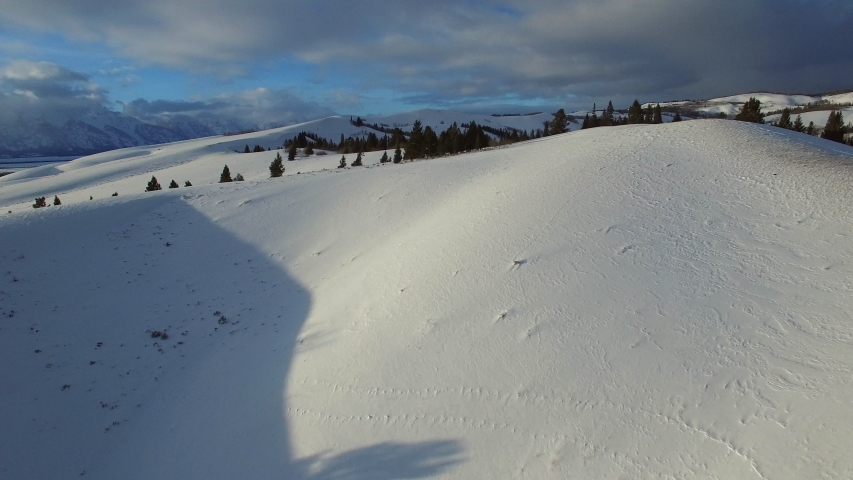 Aerial view of trees on snowcapped mountain against sky, drone moving forward over beautiful white landscape - Jackson, Wyoming