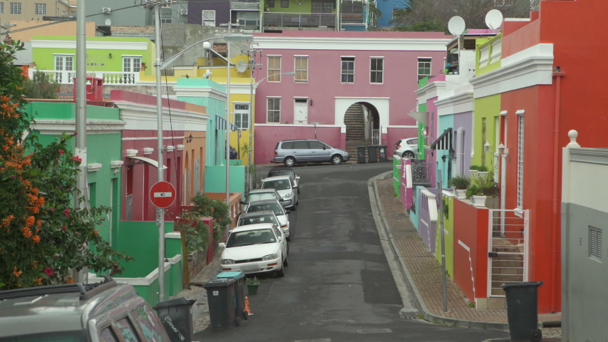 An interesting street lined with cars and brightly colored houses of various hues - Cape Town, South Africa