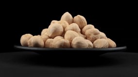 Hazelnut grains of spin around themselves on a black background and ground