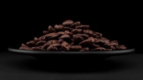 Coffee grains of spin around themselves on a black background and ground